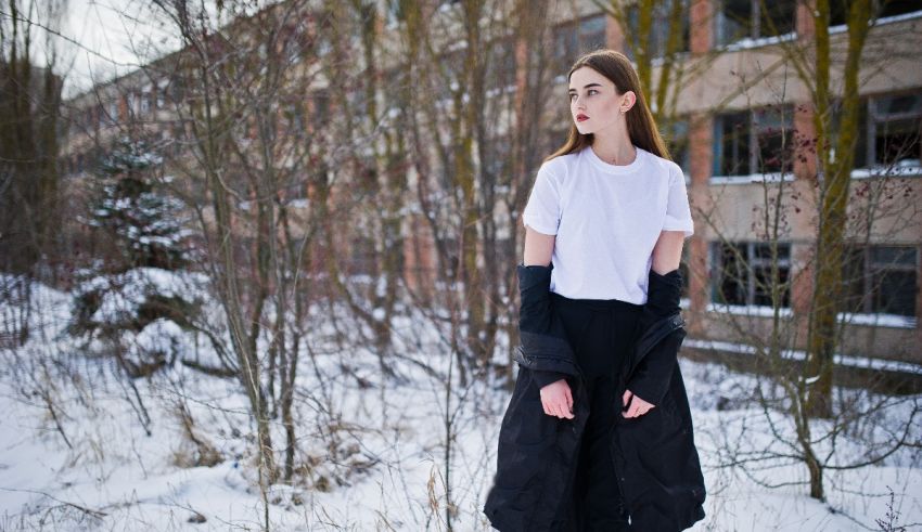 A girl in a white t - shirt standing in the snow.