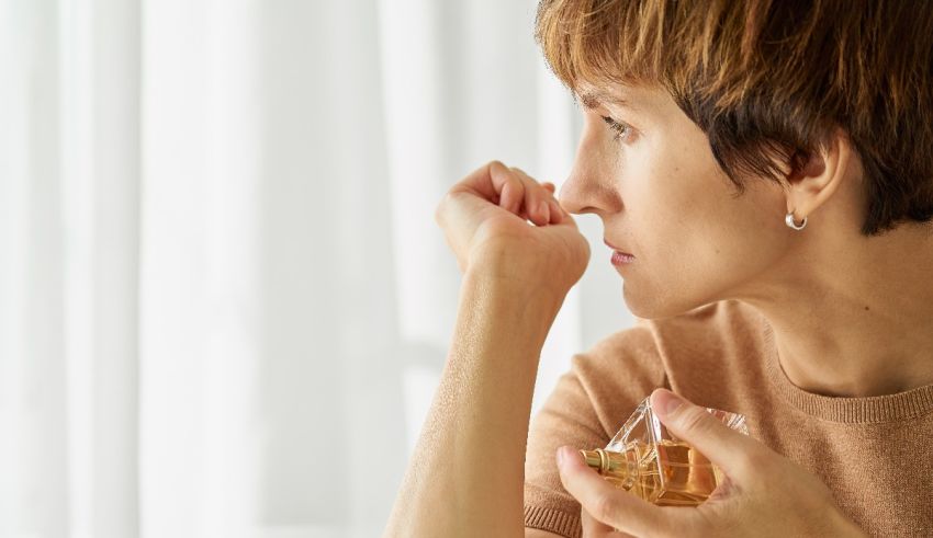 A woman is holding a glass of perfume.