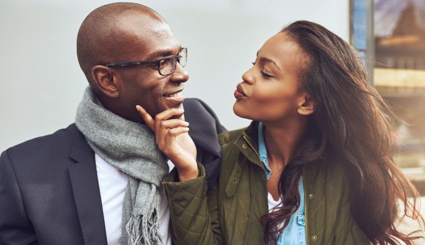 A black man and woman kissing in front of a building.