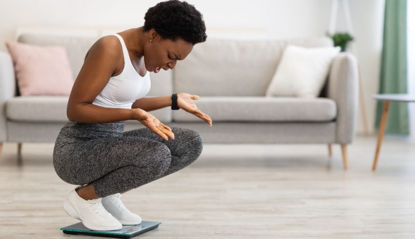 A woman is squatting on a weight scale in her living room.