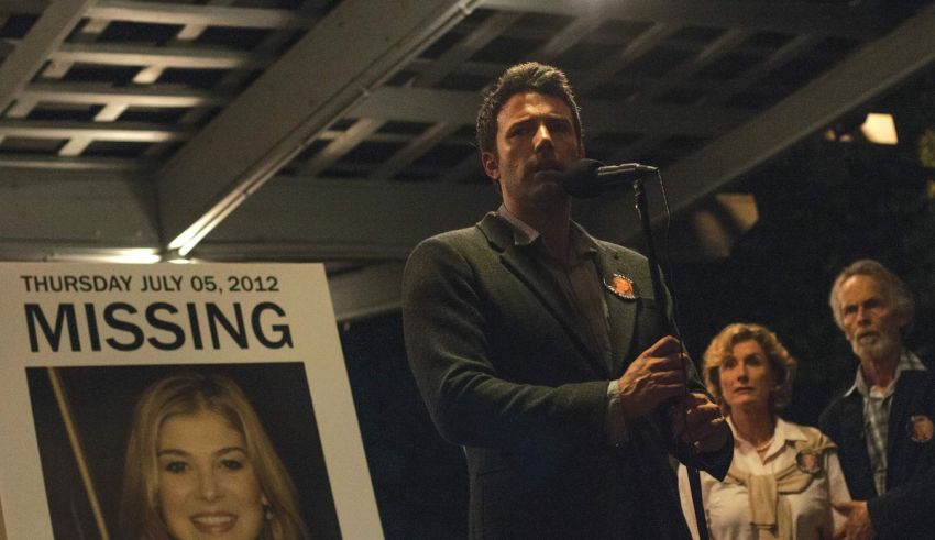 A man is standing in front of a poster for a missing person.