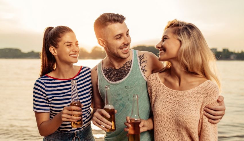 A group of friends drinking beer on a beach.