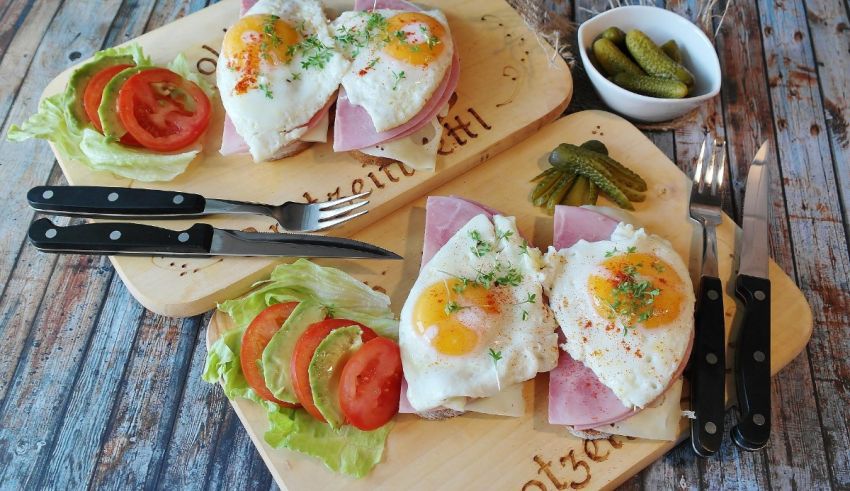 Two wooden cutting boards with ham and eggs on them.