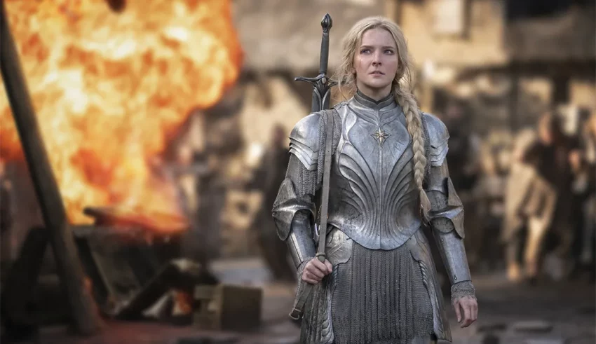 A woman in armor standing in front of a fire.