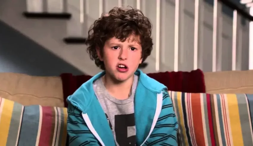 A young boy with curly hair sitting on a couch.