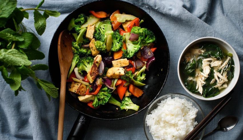 A pan with vegetables, rice and a bowl of soup.