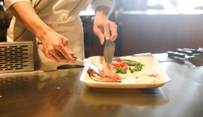 A chef cutting a piece of fish on a plate.