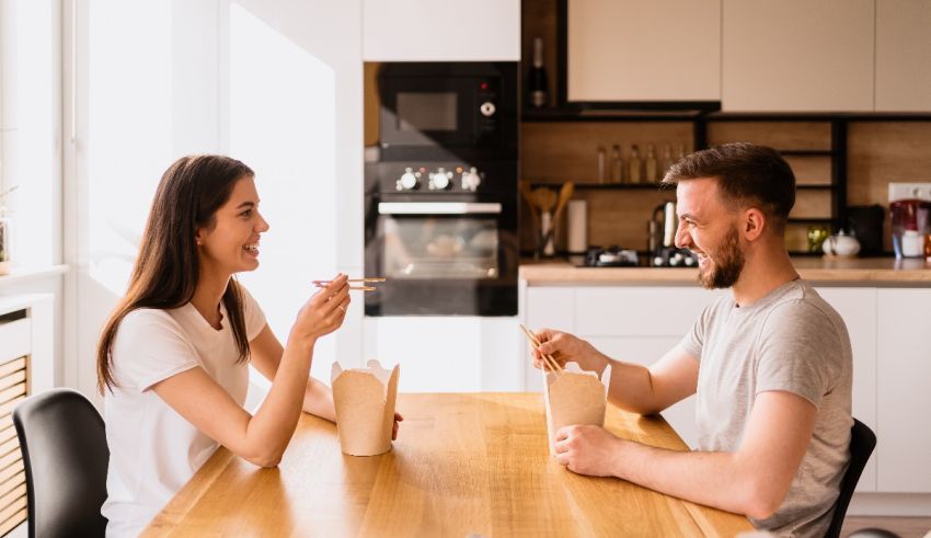 Young man and woman eating breakfast together at the kitchen table.