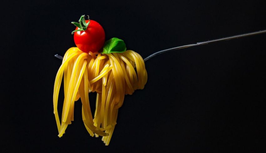 A fork with spaghetti and a tomato on it.
