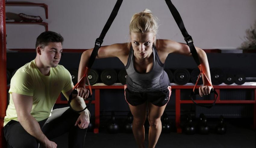 A man and woman doing a trx workout in a gym.