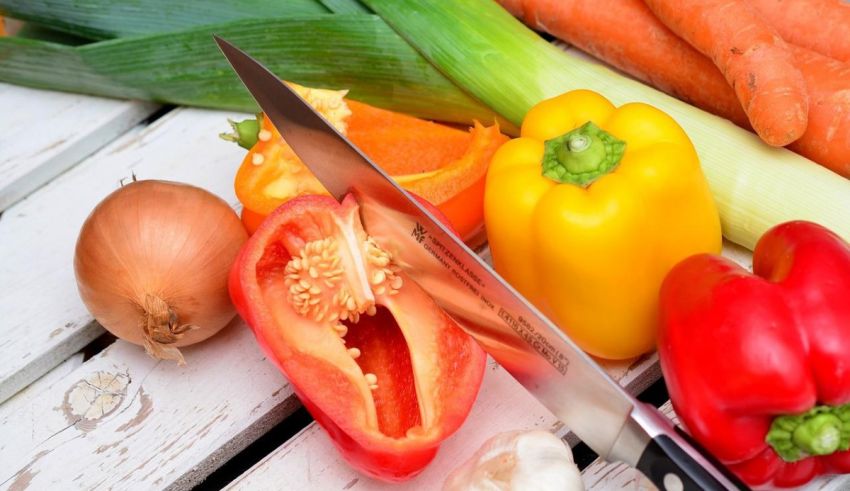 A knife sits next to a variety of vegetables.