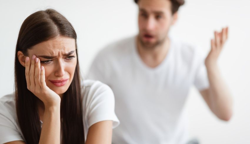 A man and a woman are arguing in front of a white background.