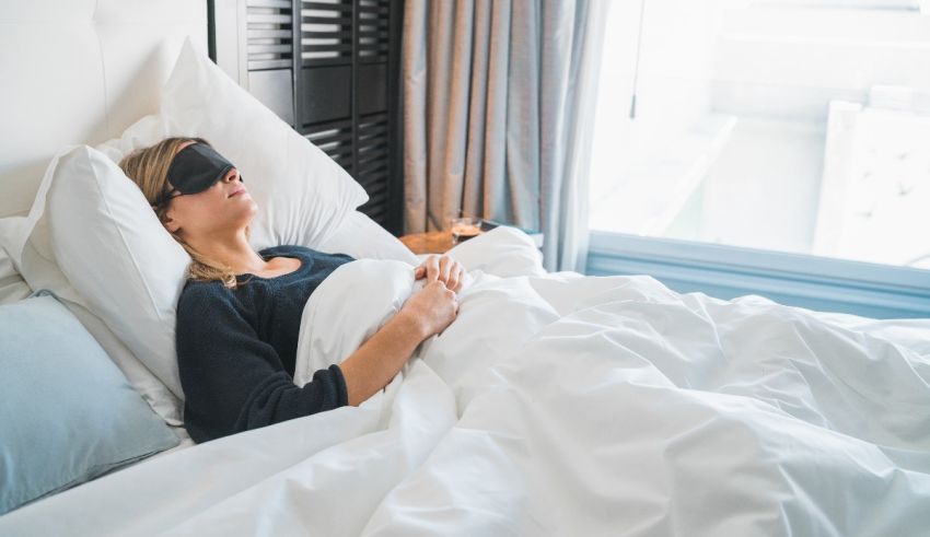 A woman is sleeping in bed with a blindfold on her face.