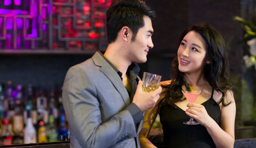 A man and a woman in a bar holding drinks.