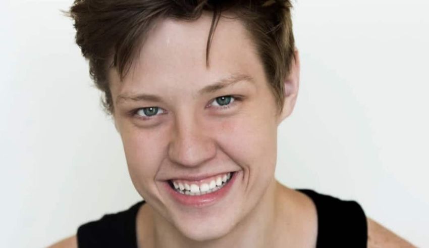 A young man smiling in a black tank top.