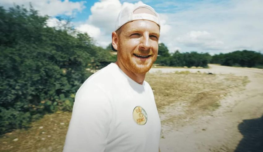 A man in a white hat standing on a dirt road.