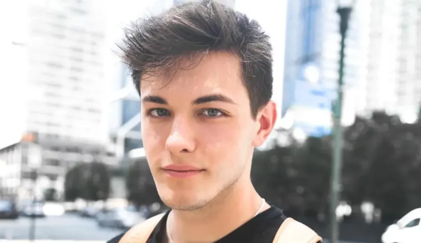 A young man is standing in front of a city.