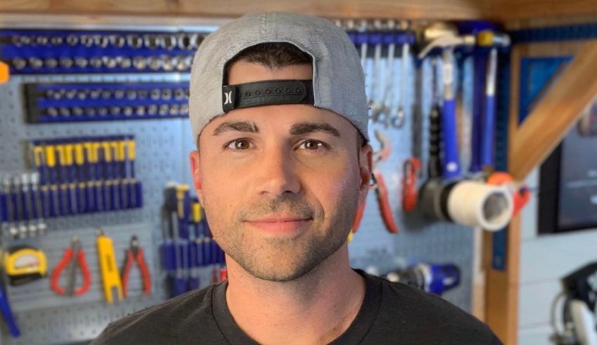 A man wearing a hat in front of tools in a garage.