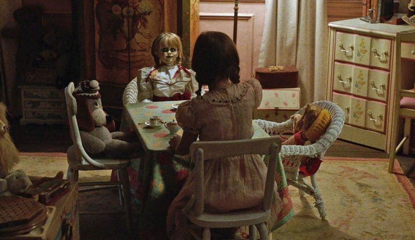 A woman sits at a table with two dolls.