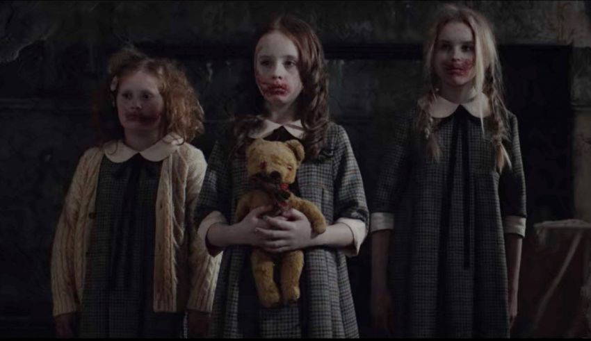 Three little girls holding a teddy bear.