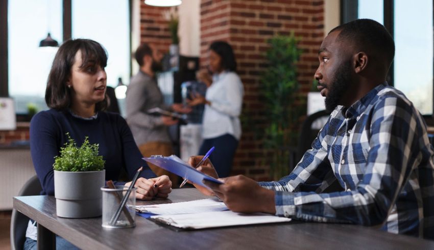 Two people talking at a table in an office.