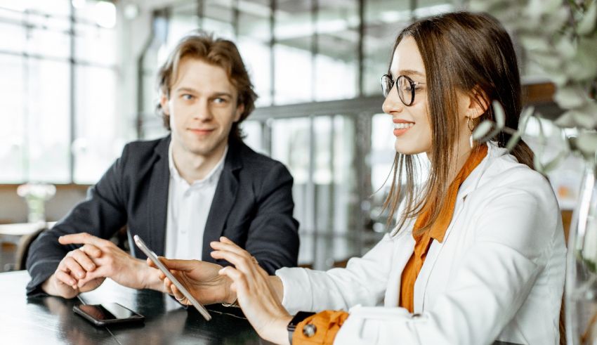 Two business people sitting at a table looking at a tablet.