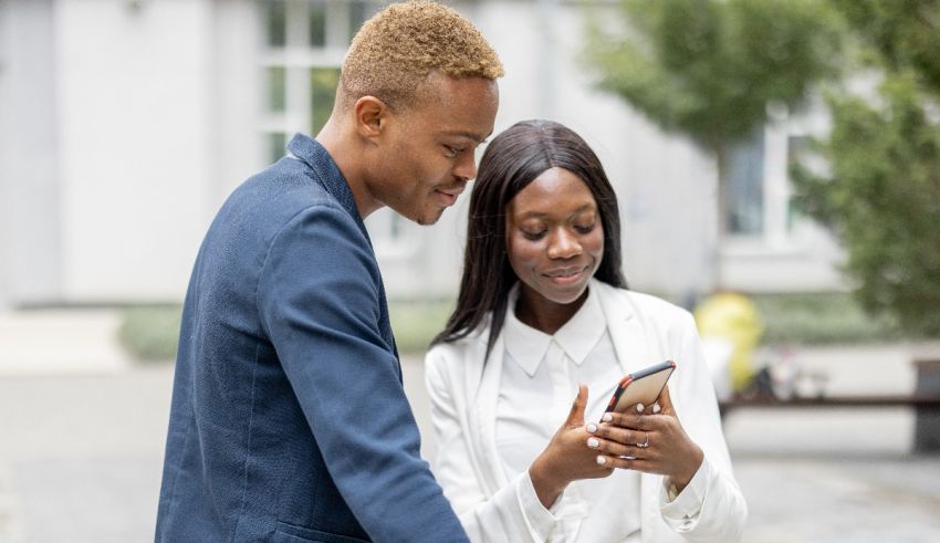 A young man and woman are looking at their cell phone.