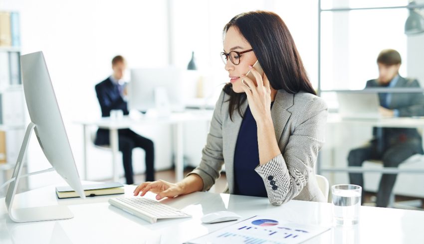 A woman is sitting at a desk in front of a computer.