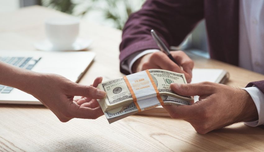 A man is handing money to a woman at a desk.