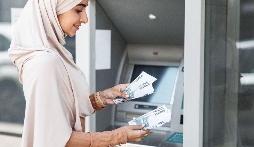 A woman wearing a hijab is standing next to an atm machine.