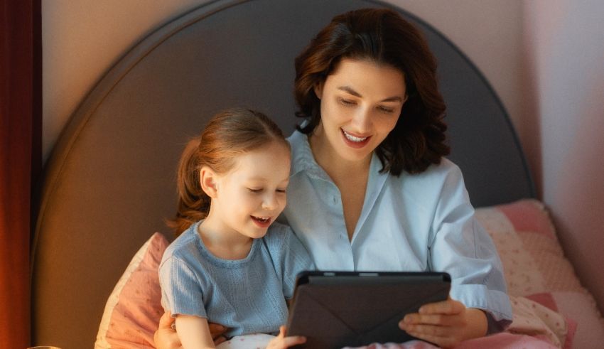 A mother and daughter using a tablet in bed.