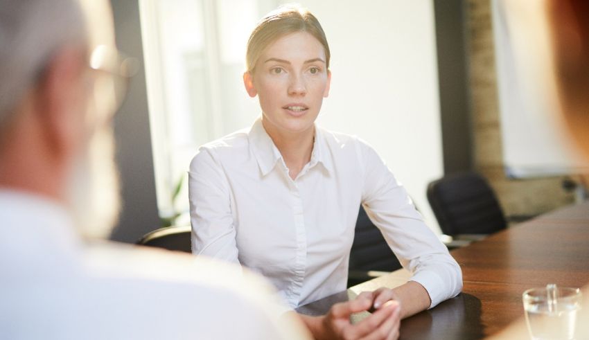 A woman is talking to a man at a conference table.