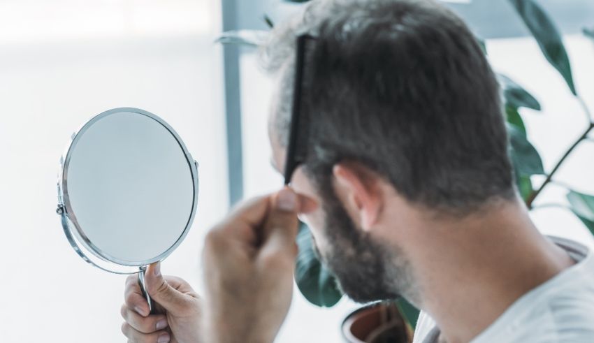 A man is combing his hair in front of a mirror.