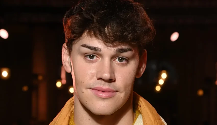 A young man with curly hair and a yellow scarf.