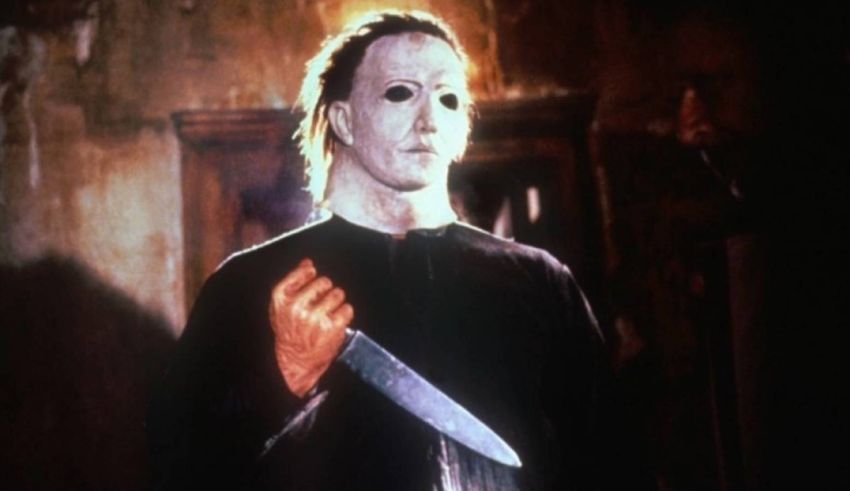 Michael myers holding a knife in front of a dark room.