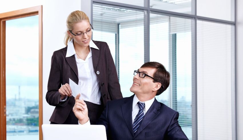 A woman and a man standing in front of a laptop in an office.