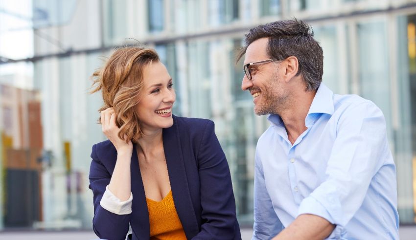 A man and woman are sitting on a bench in front of a building.