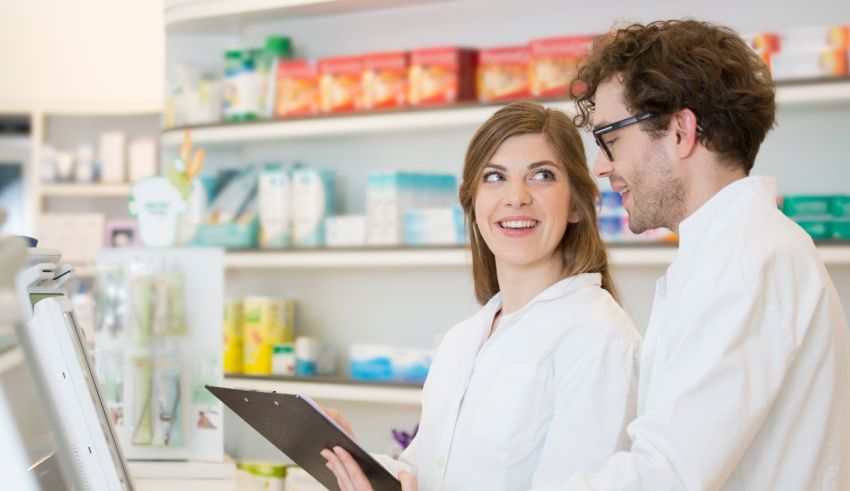 Two people in a pharmacy looking at a tablet.