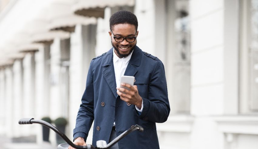 A black man on a bicycle looking at his phone.