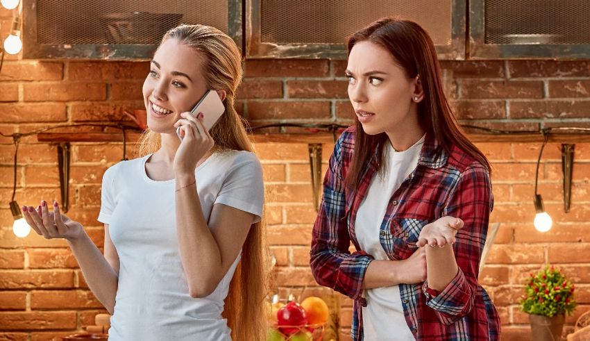 Two women talking on a cell phone in a kitchen.