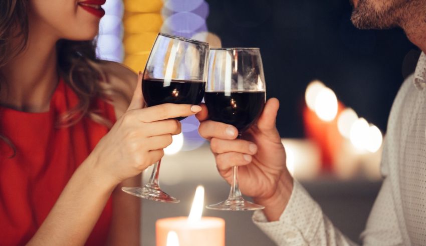 A man and woman toasting wine glasses in front of candles.
