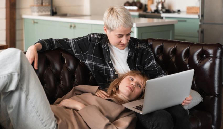 Two women sitting on a couch and using a laptop.