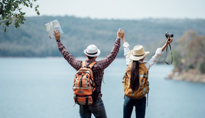 Two people with backpacks and a map standing by a lake.