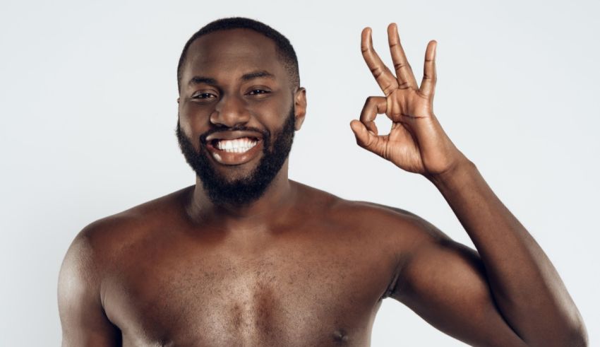 A naked black man showing the ok sign on a white background.