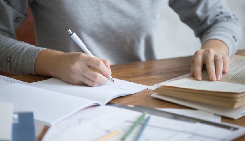 A woman is writing on a notebook with a pen.