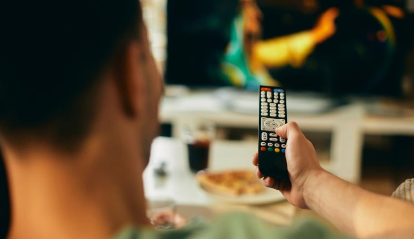 A man holding a remote control in front of a television.