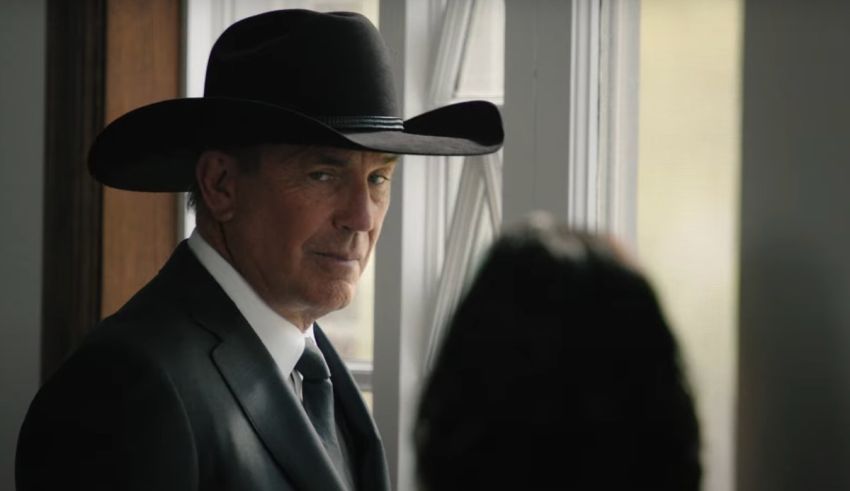 A man in a cowboy hat looking out a window.