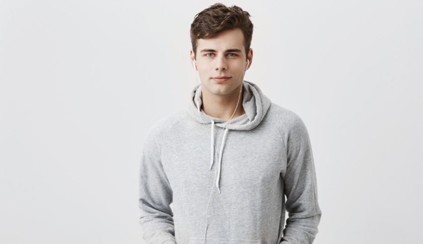 A young man wearing a grey hoodie posing against a white background.