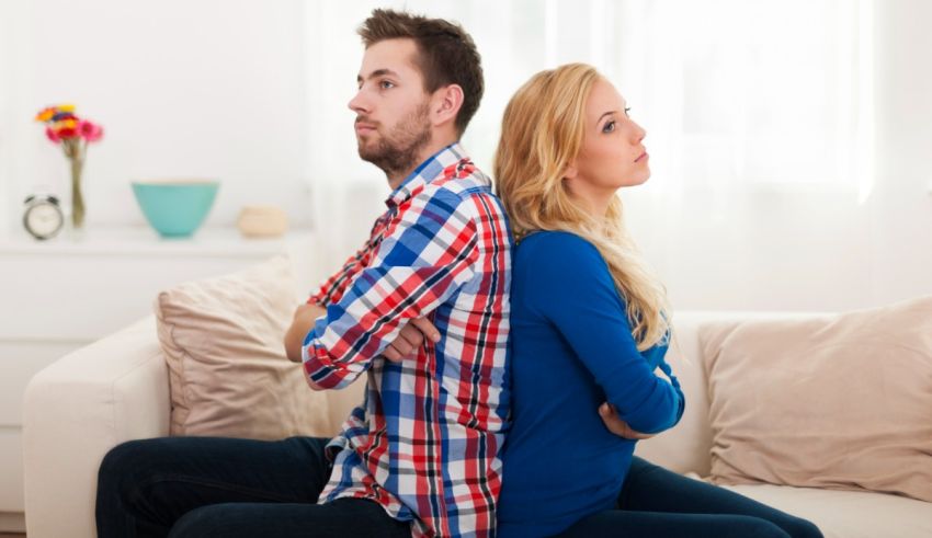 A man and woman sitting on a couch with their backs facing each other.
