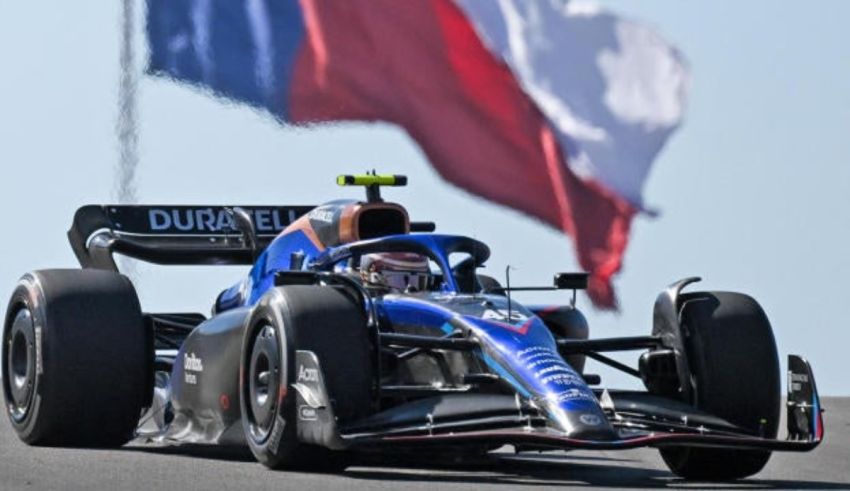 A blue racing car with a texas flag in the background.